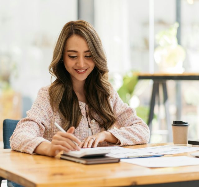 Business women using calculator at working with financial report.